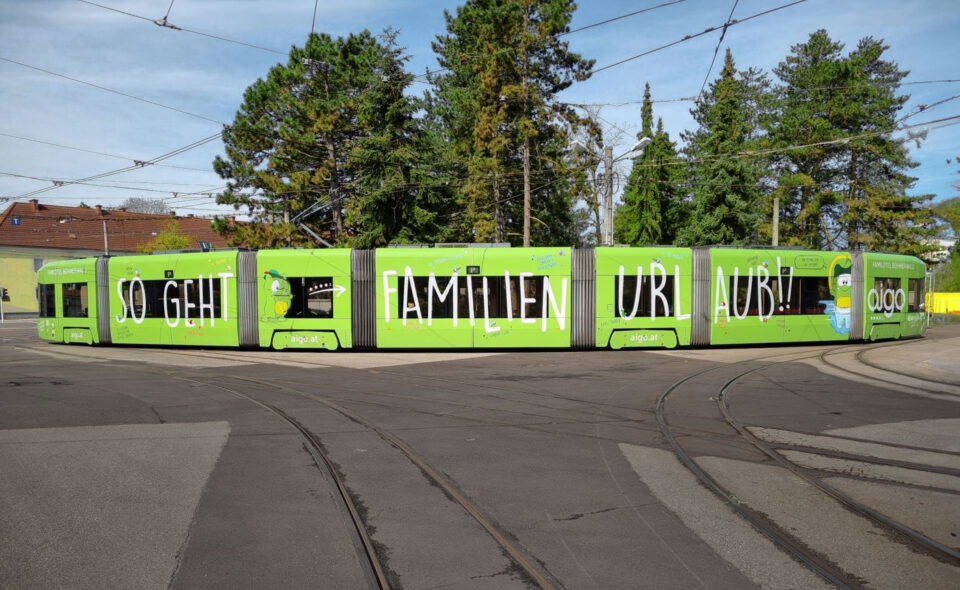 Straßenbahn mit grüner AIGO Beschriftung in Linz - AIGO Familienhotel