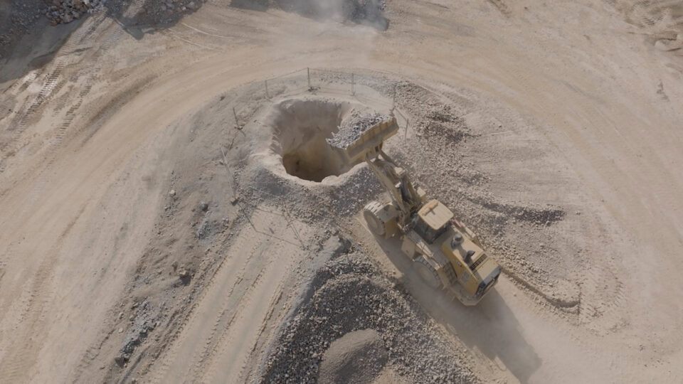 Schaufelbagger schaufelt Kalkbruch in ein Loch