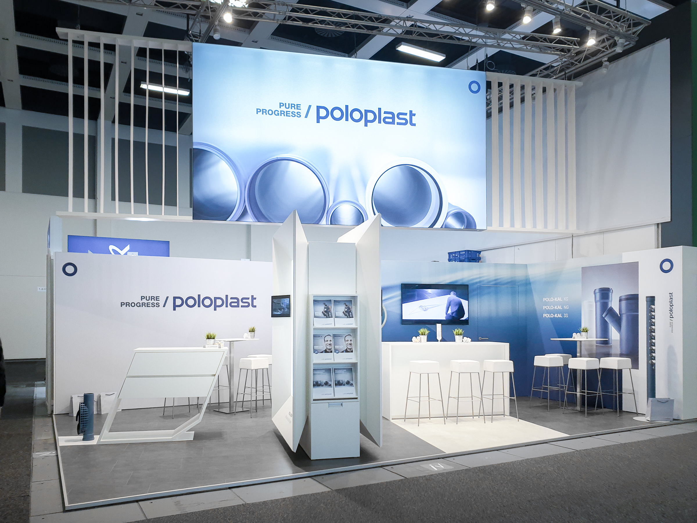 Frontale Ansicht des Poloplast-Messestands mit mehrseitigem Präsentationsmodul, Infodisplay, Prospektregal und moderner Sitzlandschaft für Fachgespräche des Verkauf-Teams